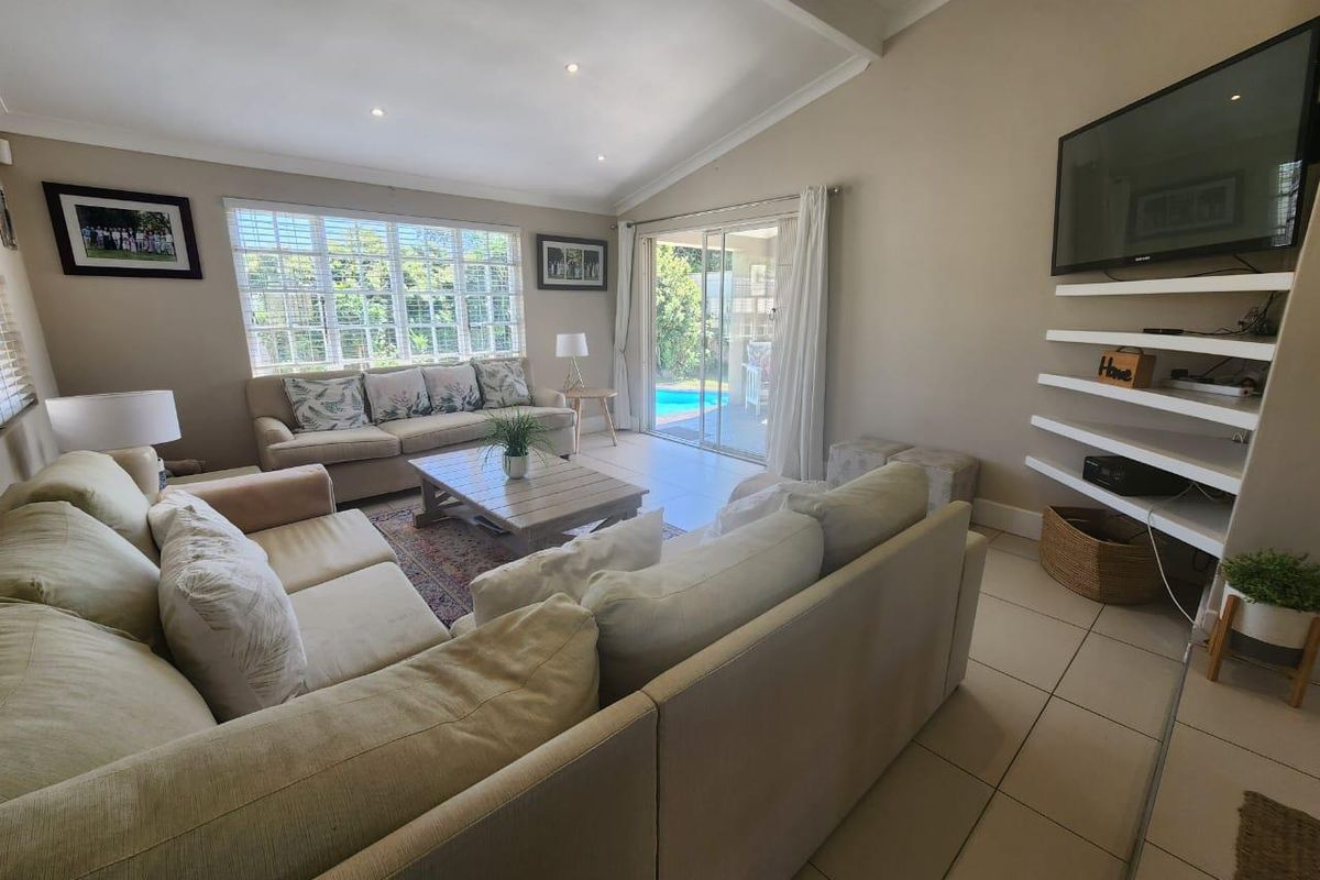 Spacious living room featuring tiled flooring, recessed ceiling lighting, and sliding glass doors providing direct access to the outdoor patio and pool area.