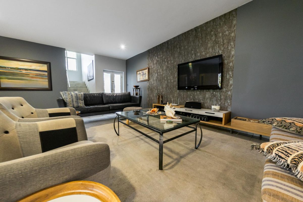 Spacious living room featuring a textured feature wall, recessed lighting, and neutral carpeting, providing a comfortable and well-defined area for relaxation.