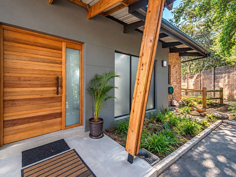 Modern townhouse entrance featuring a natural timber front door, frosted glass sidelight, and a covered porch area with exposed timber structural beams.