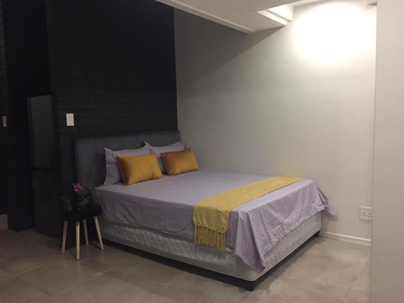 A bedroom featuring a dark exposed brick accent wall, neutral tiled flooring, and modern lighting, providing a clean and contemporary sleeping space.