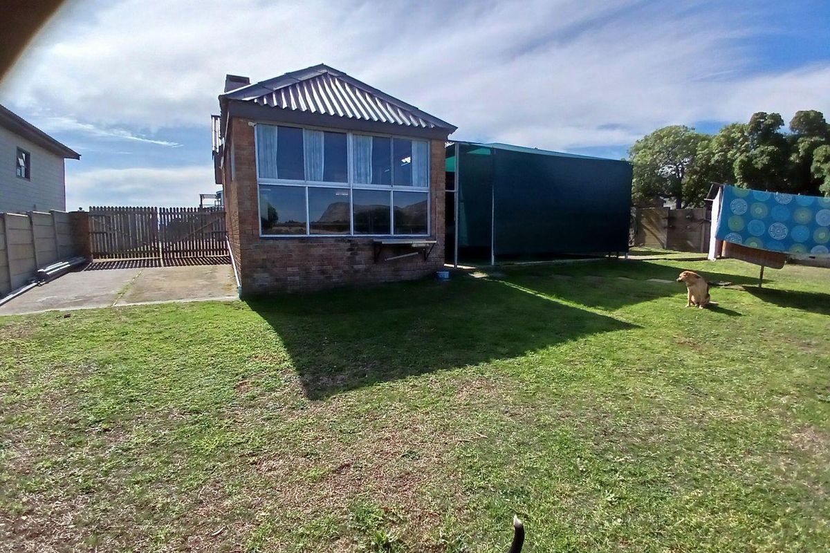 Rear view of the property featuring a brick exterior, large windows, and a spacious backyard area.