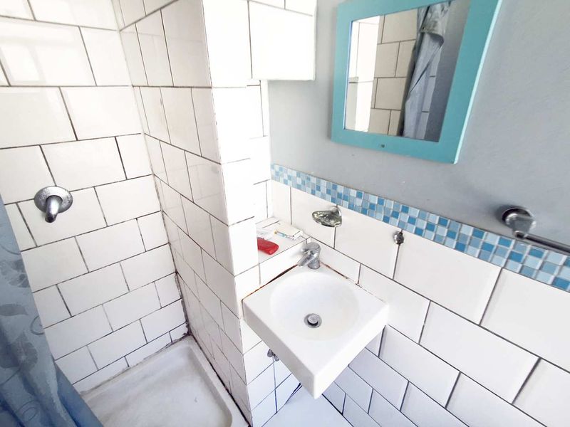 Compact bathroom featuring a shower cubicle and wall-mounted basin with decorative blue mosaic tile accents.