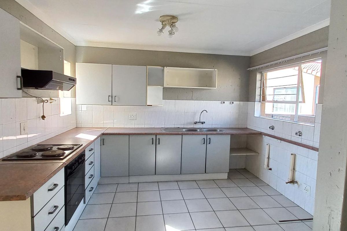 A dated kitchen featuring built-in cabinetry, laminate countertops, an electric hob, and an oven, with tiled flooring and splashbacks throughout.