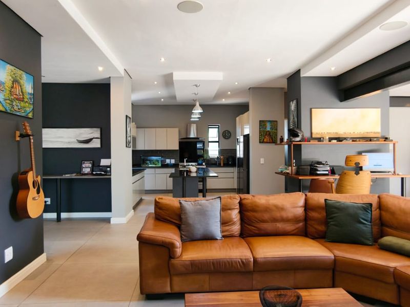 Spacious open-plan living area featuring a modern kitchen with island, recessed lighting, and seamless flow to outdoor space through large sliding glass doors.