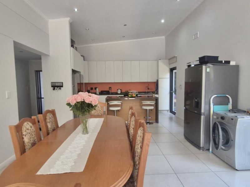 Open-plan kitchen and dining area featuring modern cabinetry, a central island, and tiled flooring, creating a functional and connected living space.