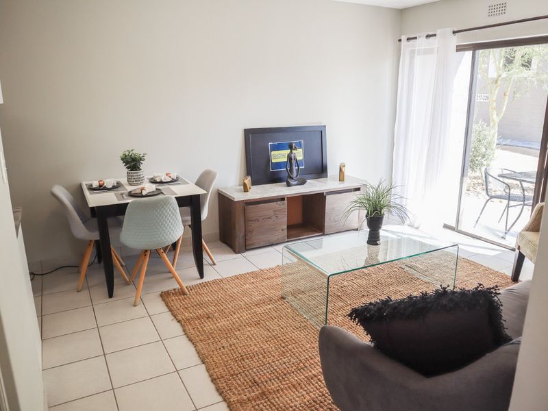 An open-plan living and dining area featuring neutral tiled flooring and a sliding glass door providing access to the outdoor space.