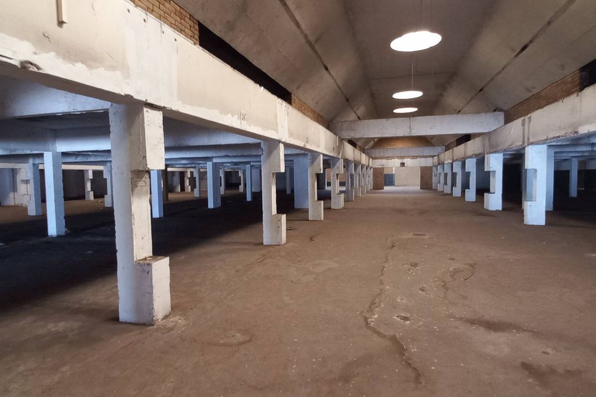 Expansive industrial warehouse space featuring high vaulted ceilings, exposed concrete structural columns, and durable concrete flooring throughout.
