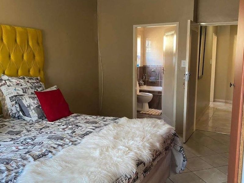 A bedroom featuring tiled flooring and coved ceilings, with direct access to an en-suite bathroom and hallway.