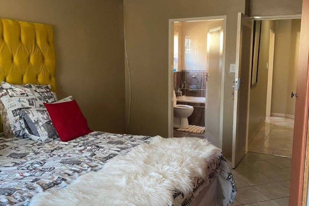 A bedroom featuring tiled flooring and coved ceilings, with direct access to an en-suite bathroom and hallway.