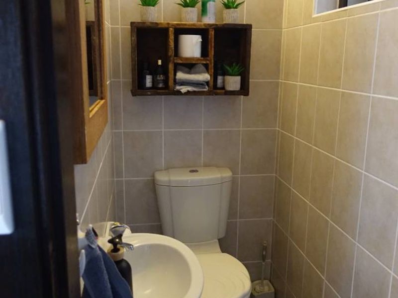 A compact, well-maintained guest bathroom featuring neutral wall tiling, a pedestal basin, and a toilet.
