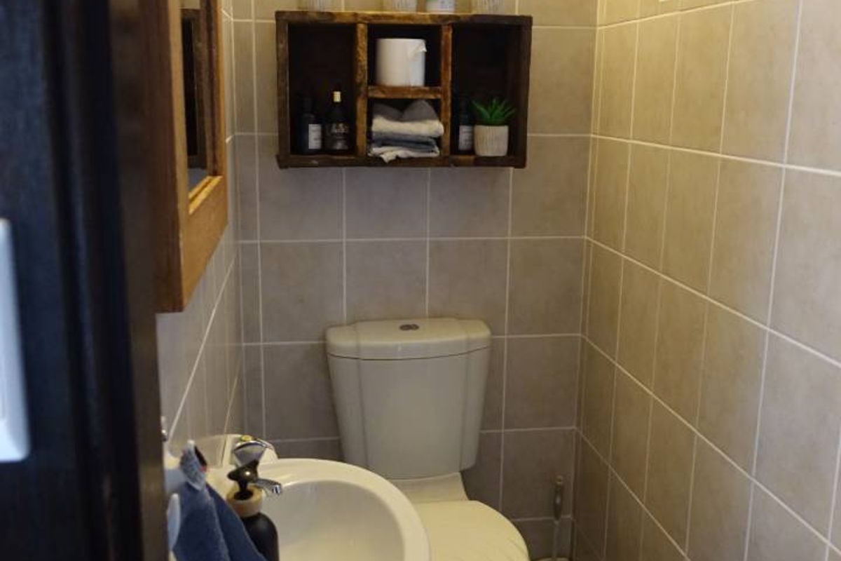 A compact, well-maintained guest bathroom featuring neutral wall tiling, a pedestal basin, and a toilet.