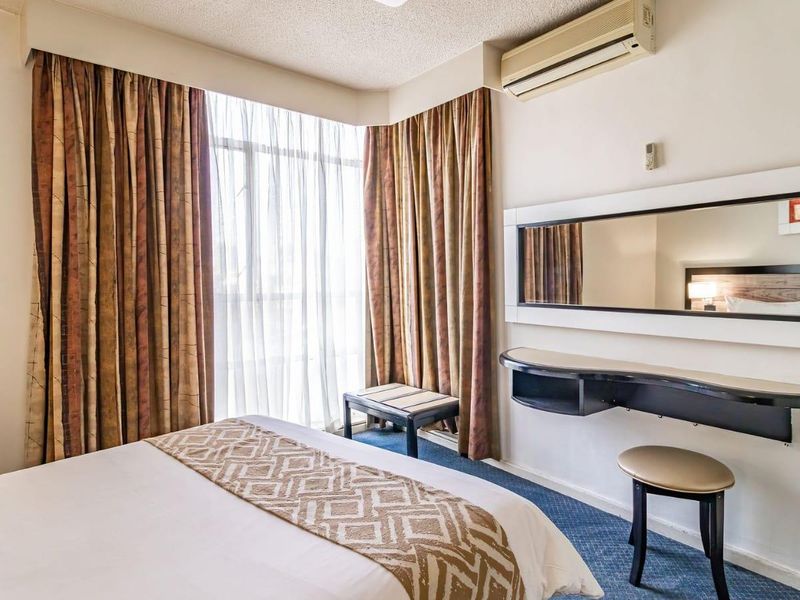 A bedroom featuring a wall-mounted air conditioning unit, built-in vanity shelf with mirror, and carpeted flooring.