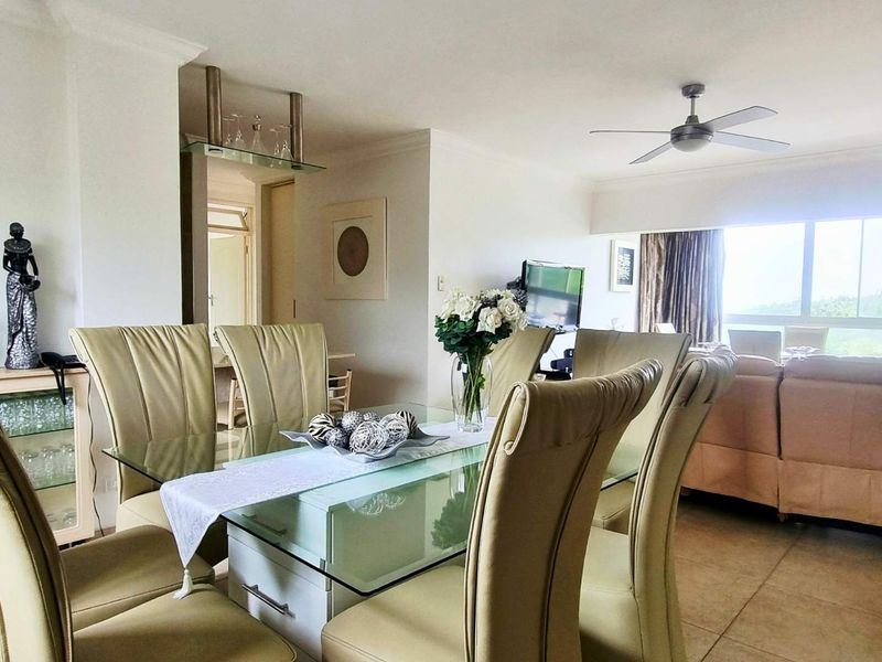 Open plan living and dining area featuring tiled flooring, a ceiling fan, and large sliding glass doors providing natural light and outdoor access.