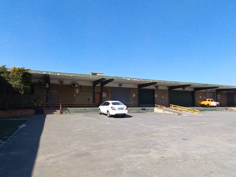Industrial warehouse facility featuring multiple loading bays, a large concrete yard area, and covered loading docks for efficient logistics and distribution operations.