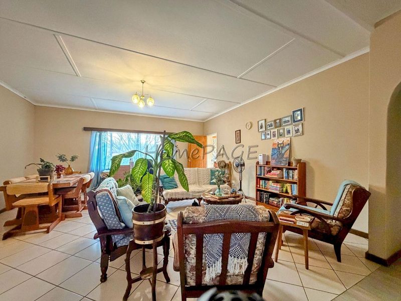 Spacious open-plan living and dining area featuring neutral wall tones, tiled flooring, and classic ceiling paneling, offering a versatile layout for family living.