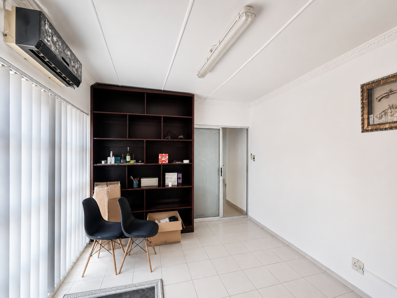 A living area featuring tiled flooring, a built-in shelving unit, an air conditioning unit, and a sliding glass door leading to an adjacent space.
