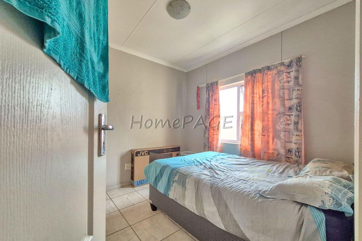 A standard bedroom featuring tiled flooring, a window with curtain tracks, and a ceiling-mounted light fixture.