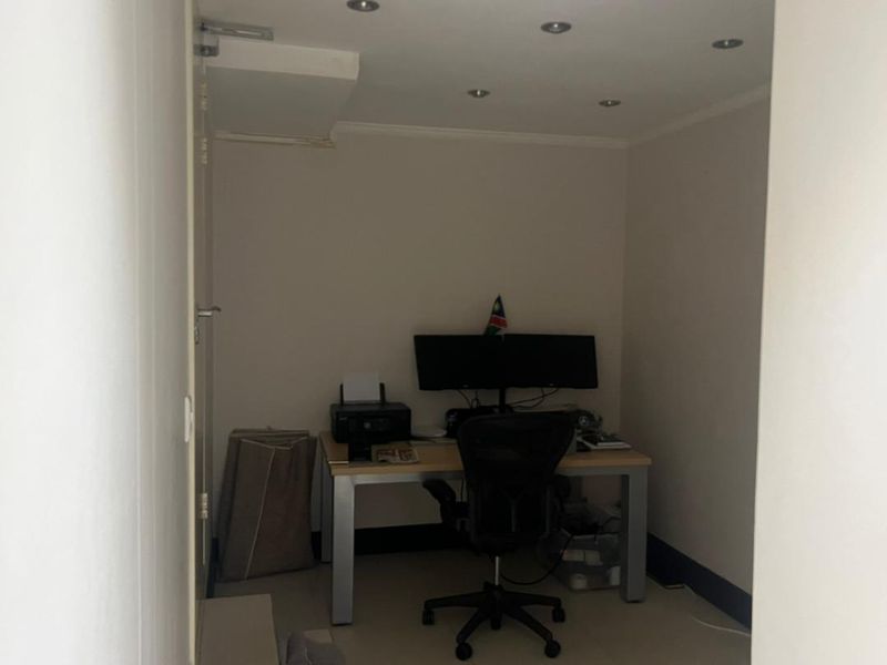 A compact home office space featuring tiled flooring and recessed ceiling lighting, suitable for a dedicated workspace or study area.