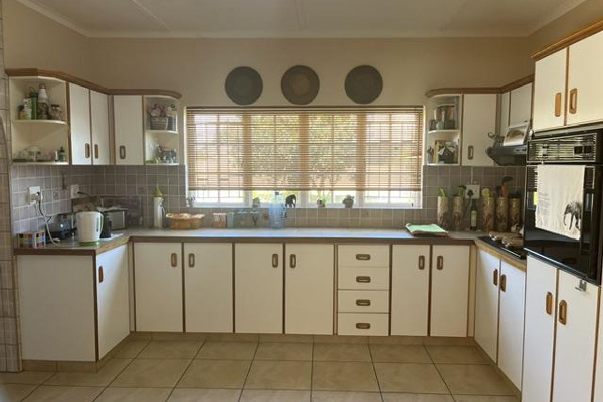 A functional kitchen featuring white cabinetry with wood trim, tiled backsplash, built-in oven, and tiled flooring, offering a classic layout with ample storage.