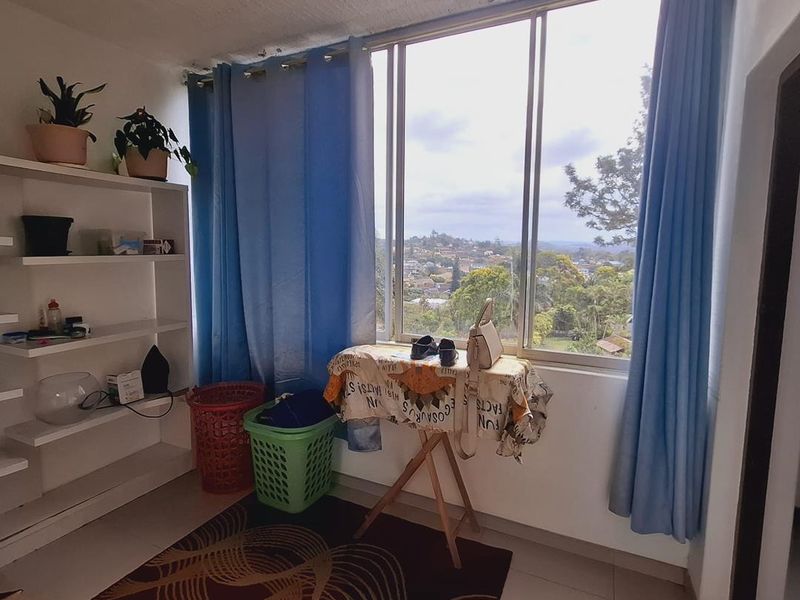 A functional utility space featuring built-in shelving, tiled flooring, and a large window offering scenic neighborhood views.
