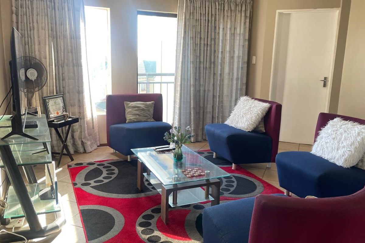 A living room area featuring tiled flooring and a sliding door providing access to a balcony, offering natural light and a functional layout.