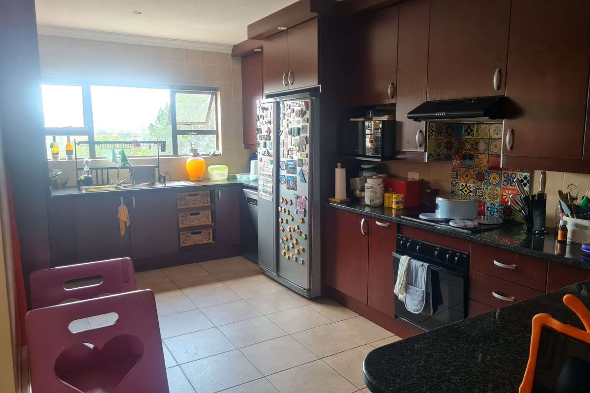 A functional kitchen featuring dark wood cabinetry, granite countertops, a built-in oven with extractor fan, and a tiled backsplash.