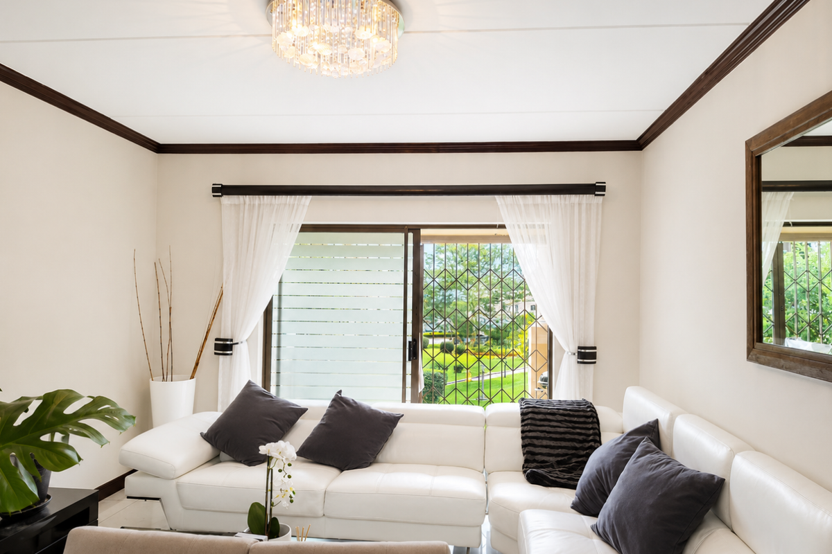 Bright living room featuring tiled floors, crown molding, a crystal chandelier, and a sliding glass door with security gate leading to the garden.