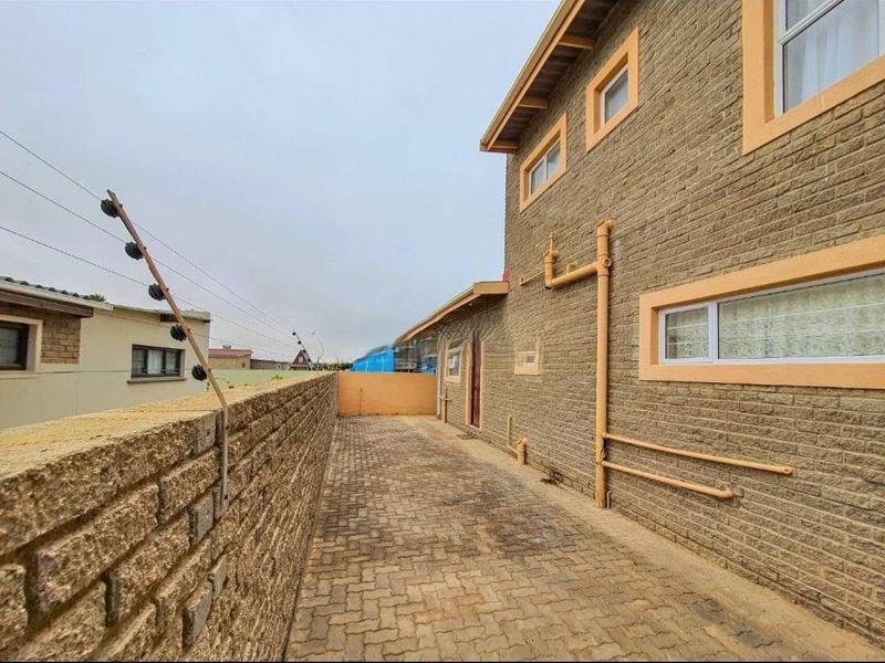 Side passage of the townhouse featuring brick paving, face brick exterior walls, and perimeter electric fencing.
