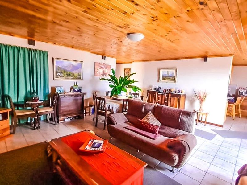 Spacious open-plan living and dining area featuring a warm timber tongue and groove ceiling and neutral tiled flooring throughout.