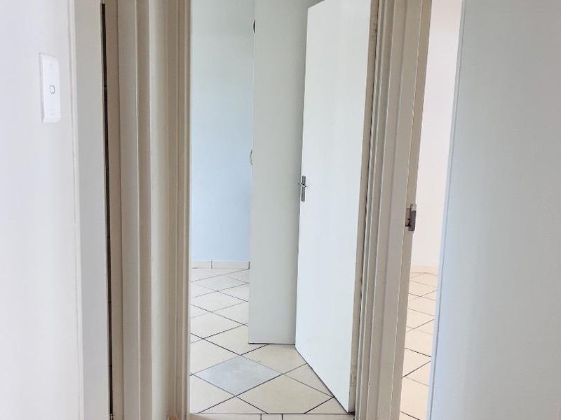 A functional hallway featuring tiled flooring and multiple internal doorways providing access to adjacent rooms.