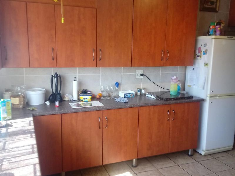 A functional kitchen featuring wood-look laminate cabinetry, durable countertops, and a neutral tiled backsplash, providing ample storage and workspace.
