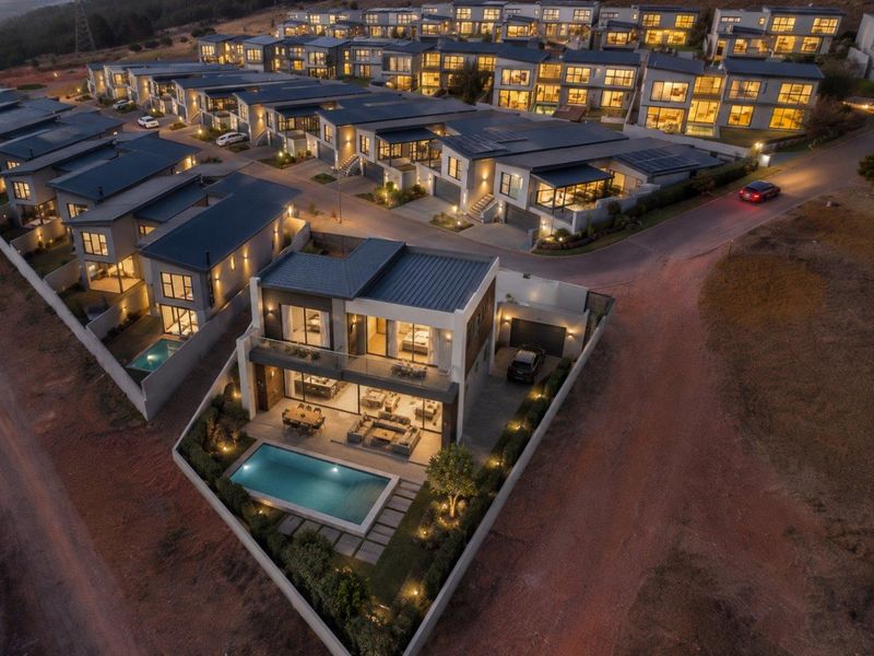 Aerial view of a modern residential estate at dusk, featuring contemporary homes with private swimming pools, landscaped gardens, and integrated solar energy systems.