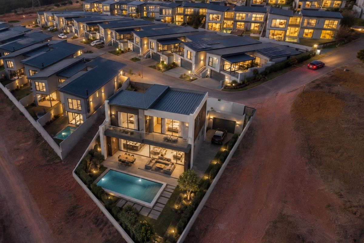 Aerial view of a modern residential estate at dusk, featuring contemporary homes with private swimming pools, landscaped gardens, and integrated solar energy systems.
