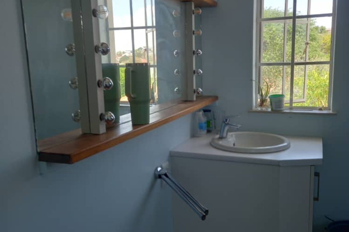 A functional bathroom vanity area featuring a built-in sink, vanity cabinet, and a large wall-mounted mirror with integrated lighting.