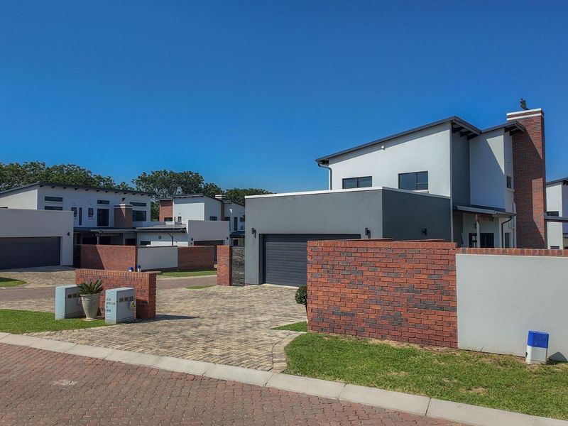 Modern residential property featuring a paved driveway, brick boundary walls, and a contemporary facade with an integrated garage.