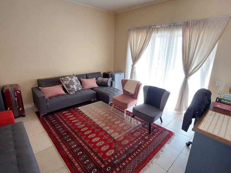 A living room featuring tiled flooring and a large sliding glass door that provides natural light.