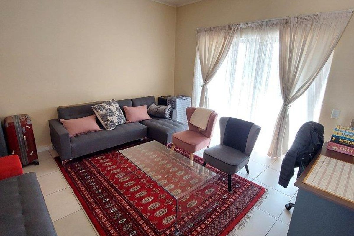 A living room featuring tiled flooring and a large sliding glass door that provides natural light.