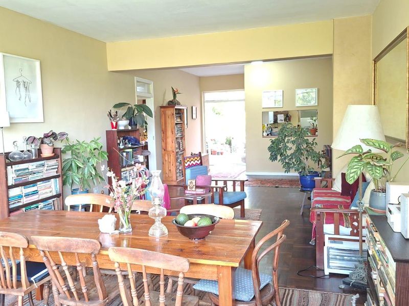 Spacious open-plan living and dining area featuring warm hardwood flooring and a seamless flow towards the rear of the apartment.