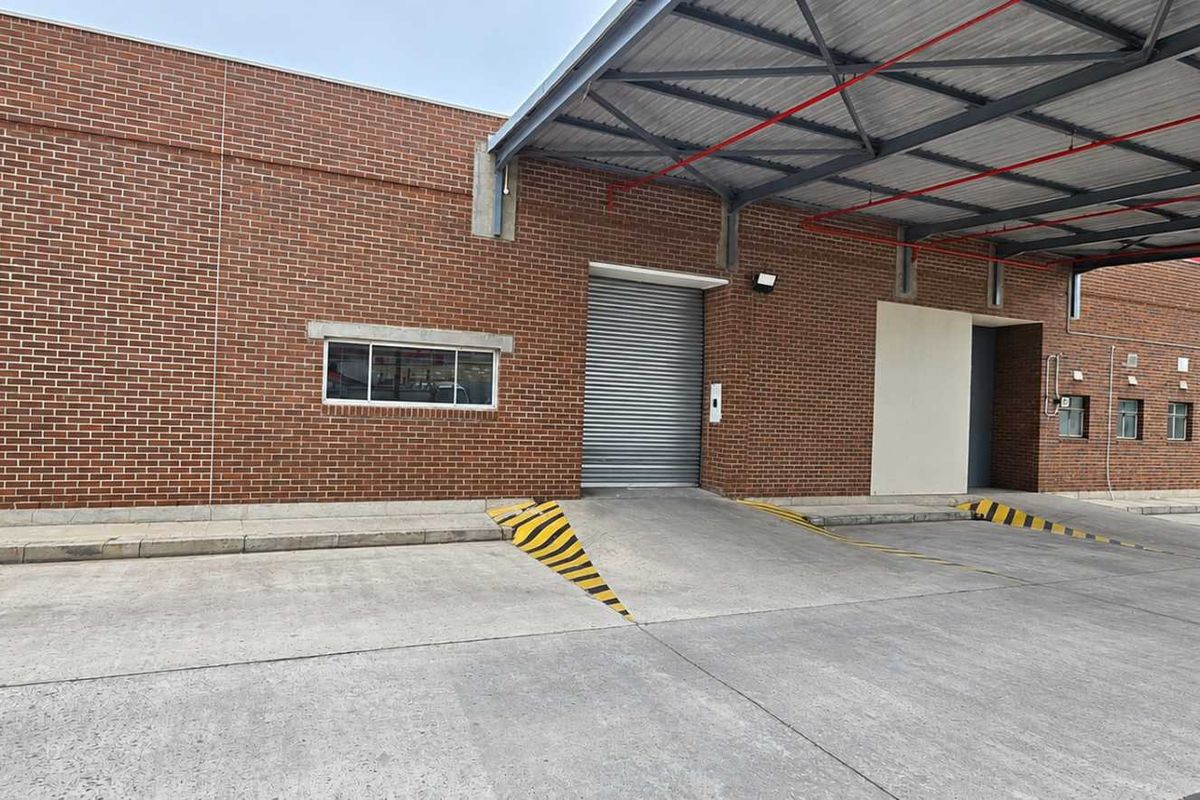 Industrial loading bay area featuring multiple roller shutter doors, a covered loading canopy, and durable concrete hardstand for efficient logistics operations.