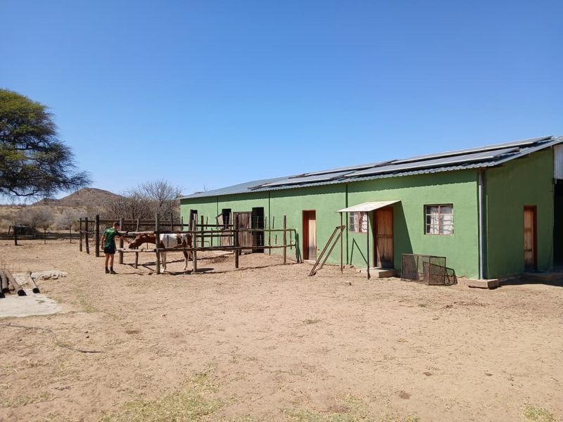 Exterior view of a small holding stable block featuring a metal roof with integrated solar panels and timber fencing.