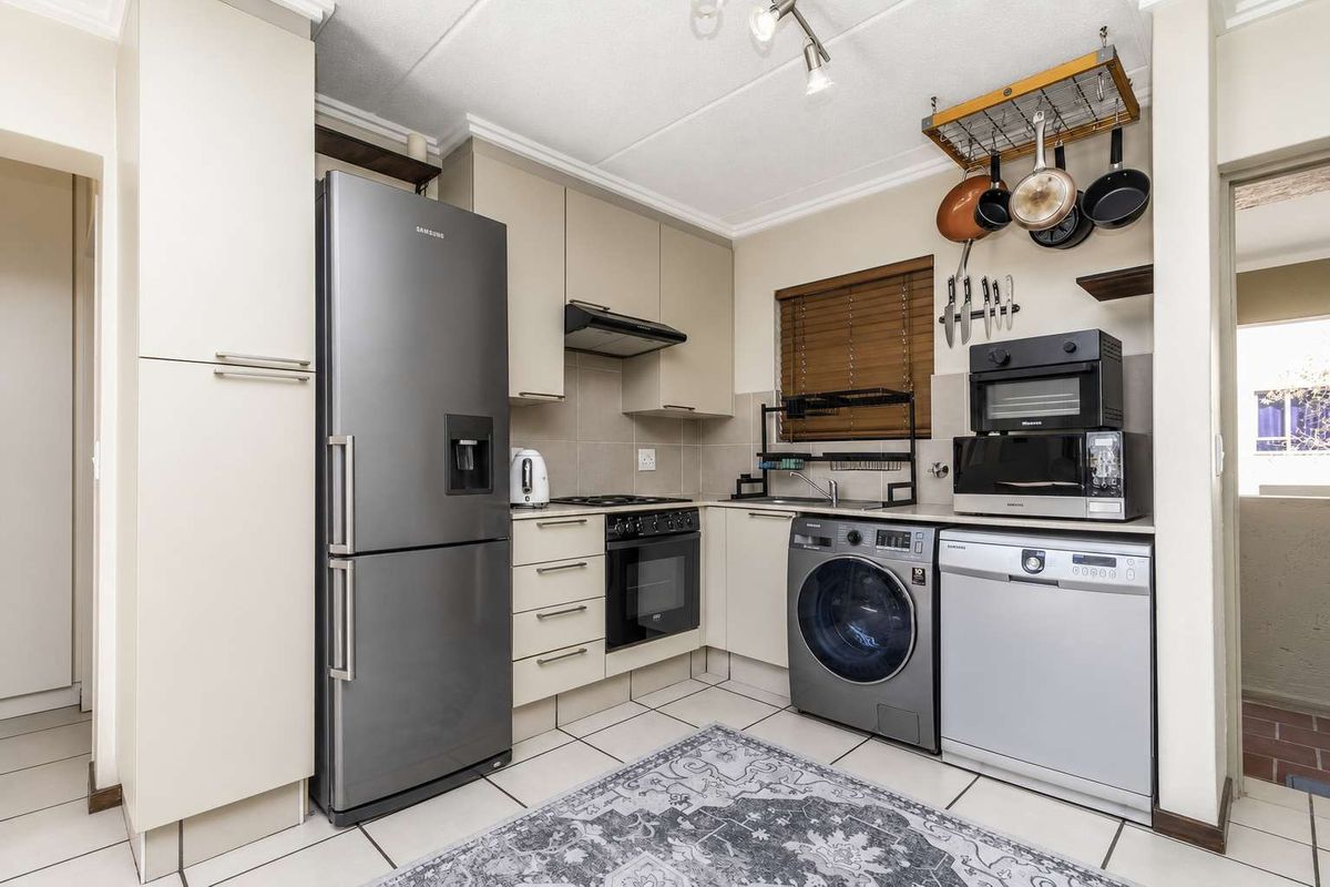 A functional kitchen featuring neutral cabinetry, tiled flooring, a tiled backsplash, and integrated space for laundry and dishwashing appliances.
