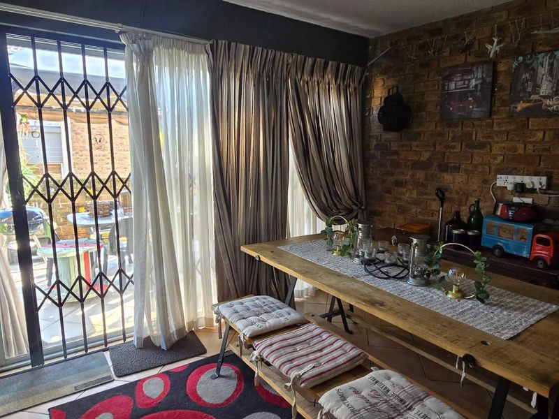Dining area featuring an exposed brick feature wall and a sliding glass door with a security gate leading to the patio.