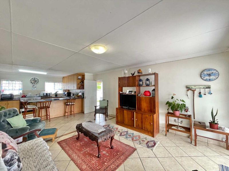 Spacious open-plan living area featuring tiled flooring and a functional kitchen with breakfast bar, offering a versatile layout for modern living.