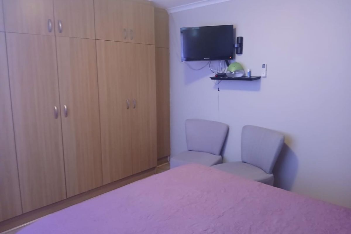 A bedroom featuring built-in wooden cabinetry and a wall-mounted television.
