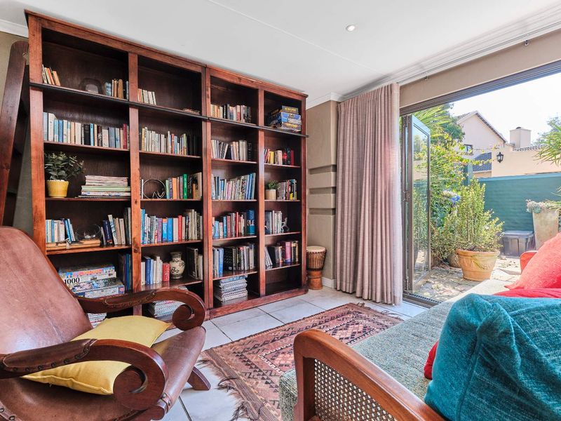 A cozy living room featuring a large built-in wooden bookshelf, tiled flooring, and a sliding glass door providing direct access to the outdoor patio area.
