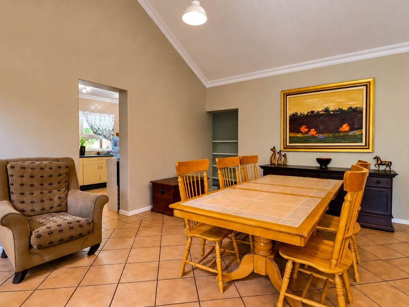 Spacious dining room featuring a high vaulted ceiling, tiled flooring, and elegant cove cornicing, with an open transition into the adjacent kitchen area.