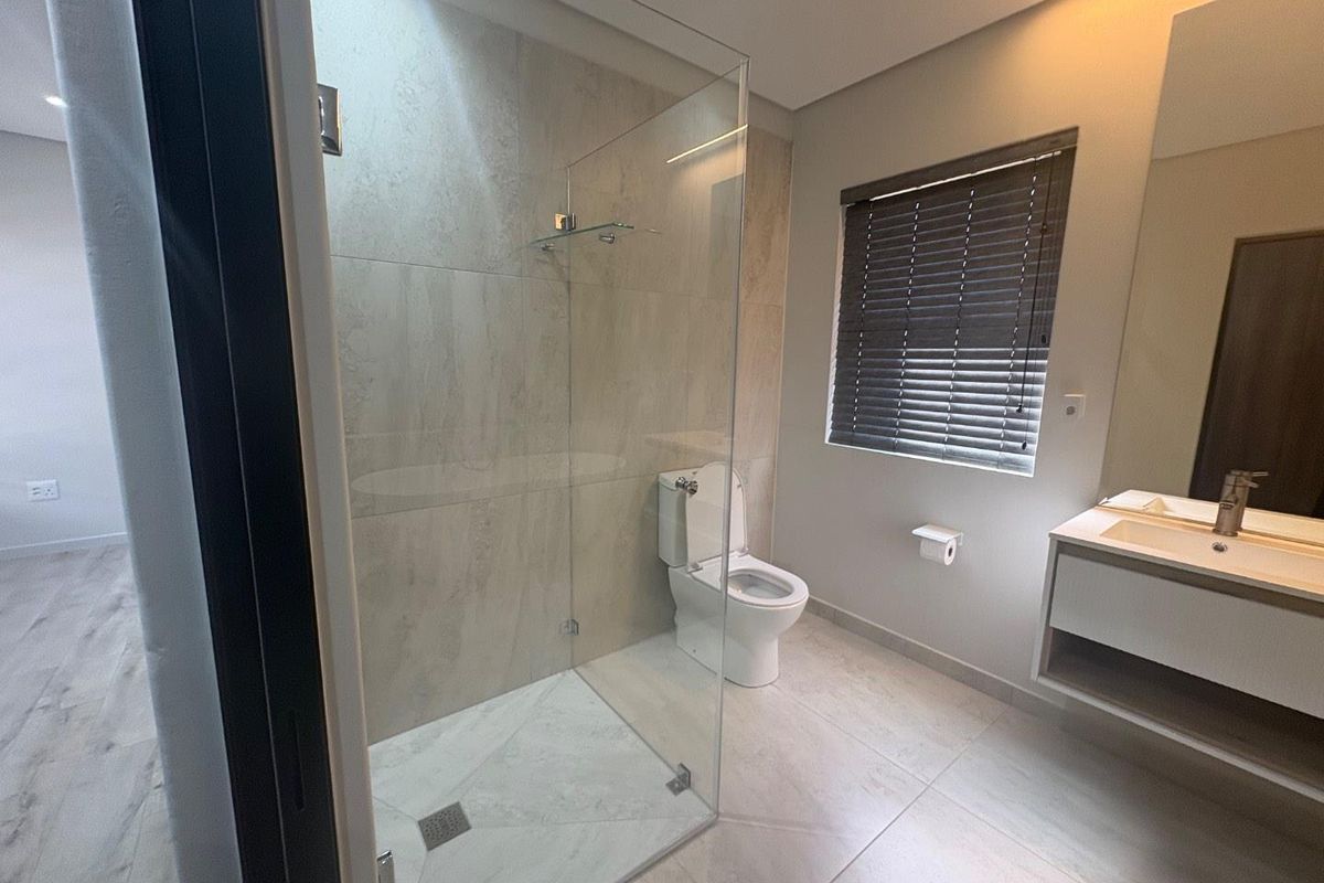 Modern bathroom featuring a glass-enclosed shower, wall-mounted toilet, and a sleek vanity cabinet with a basin.