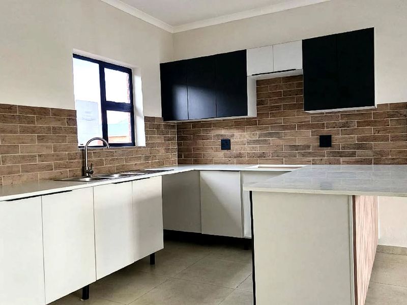 Modern kitchen featuring sleek white lower cabinetry, contrasting black upper cabinets, stone countertops, and a stylish brick-look tiled splashback.