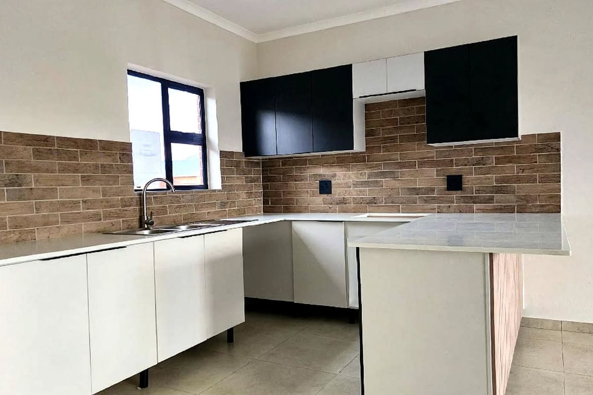 Modern kitchen featuring sleek white lower cabinetry, contrasting black upper cabinets, stone countertops, and a stylish brick-look tiled splashback.