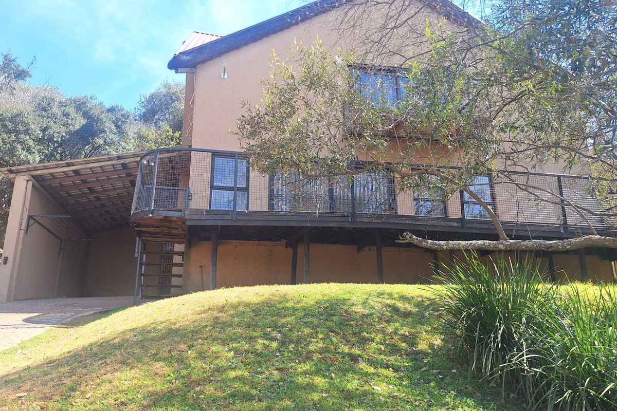Rear view of the property featuring a raised timber deck with metal balustrades, a spiral staircase, and an adjacent covered carport area.